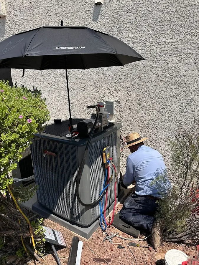 HVAC technician performing outdoor AC maintenance in Lowell